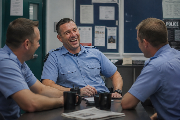 Police officers sharing a laugh together at a station, illustrating the role of dark humour in policing.