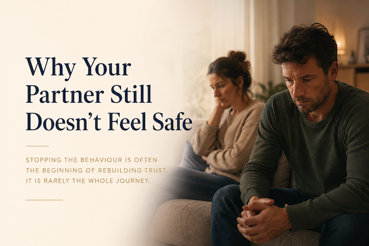 A distressed couple sitting apart on a couch, illustrating the emotional impact of broken trust and the journey to rebuilding emotional safety.
