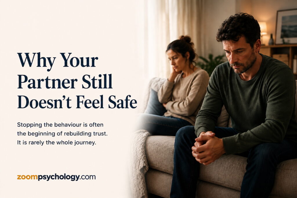 A distressed couple sitting apart on a couch, illustrating the emotional impact of broken trust and the journey to rebuilding emotional safety.